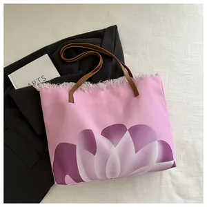 Detalle del bolso tote de lona rosa con estampado de loto púrpura y borde deshilachado