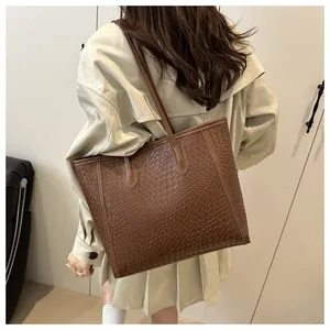 Sac cabas marron à texture tressée porté à l'épaule avec une vue arrière élégante