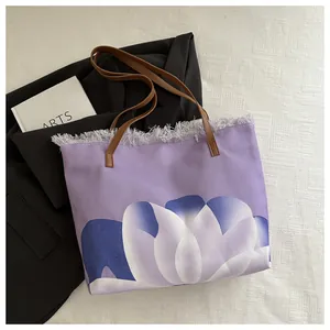 Detalle del bolso tote grande con estampado floral, flecos grises y asas marrones
