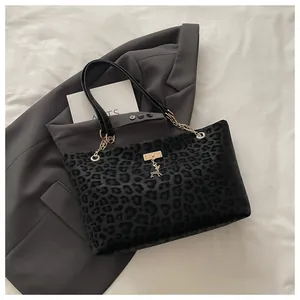 Dettaglio della borsa tote leopardata nera con ciondolo a cervo dorato e catena