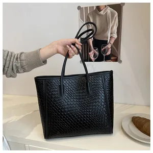 Gros plan sur la texture tressée noire et la poignée renforcée de ce sac cabas élégant