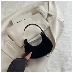 Detail of black crescent bag with suede texture and decorative gold side rivets
