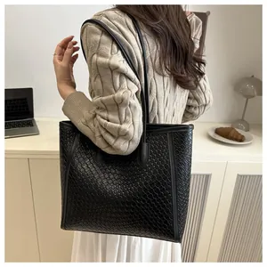 Détail du grand sac cabas noir tissé avec une structure rigide et une bandoulière chic