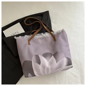 Detalle del bolso de lona lavanda con estampado floral y borde de flecos deshilachado