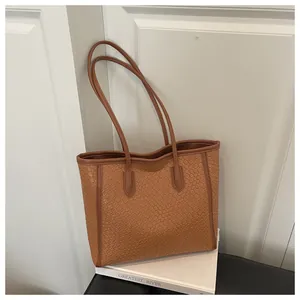 Détail d'un sac cabas marron avec texture crocodile de luxe et doubles bandoulières