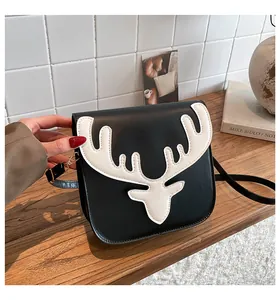 Détail du sac en cuir noir avec broderie tête de renne blanche et finitions dorées brillantes