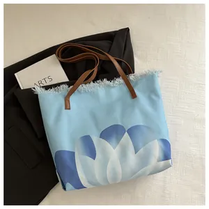 Detalle del bolso de lona con estampado floral azul y bordes deshilachados de moda