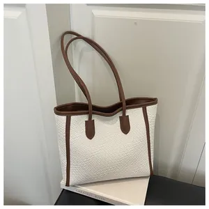 Détail de la texture tressée du sac cabas en cuir blanc avec anses marron