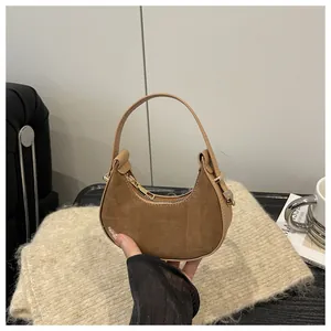 Detail of retro crescent bag featuring brown suede texture and golden metal zipper