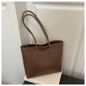 Vue détaillée de la texture tissée marron sur un cabas moderne à fines bandoulières