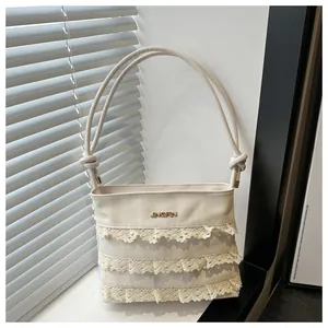 Detail of white lace mesh tote bag with three-layer ruffled texture and metallic logo
