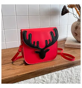 Détail du sac à bandoulière en cuir PU rouge avec décor de cornes d'élan sur table en bois