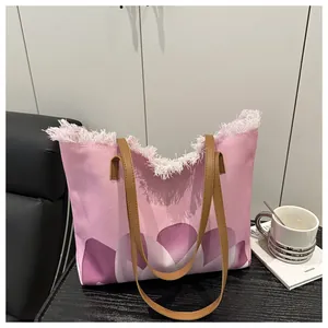 Detalle del bolso tote de lona rosa con bordes deshilachados y estampado de flores