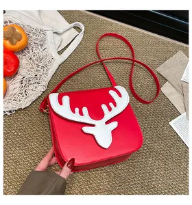 Détail d'un petit sac bandoulière rouge avec motif bois de cerf blanc sur fond chaud