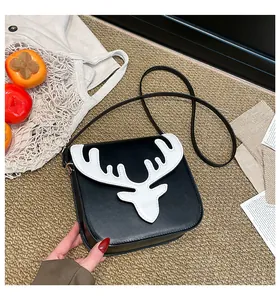 Détail de l'empiècement en cuir tête de cerf sur un sac bandoulière noir et blanc