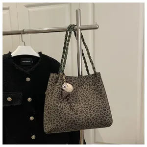 Detail of leopard print tote bag with green woven handles and cute plush charm