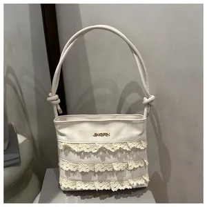 Detail of cream lace ruffle shoulder bag with checkered fabric and gold logo accent