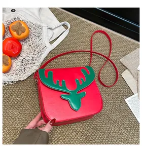Détail du sac à bandoulière rouge festif avec écusson renne vert sur un tapis texturé