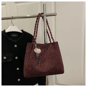 Close-up of leopard print tote bag with wine red woven handles and ice cream charm