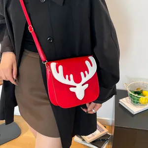 Sac bandoulière rouge avec bois de renne blancs et détails dorés porté par un mannequin