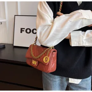 Dettaglio borsa trapuntata rosso mattone con catena dorata e pendente logo CH