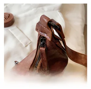 Gros plan du sac en cuir marron vintage montrant la fermeture éclair en bronze foncé