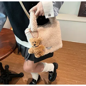Close-up of beige fuzzy faux fur bucket bag with a cute brown teddy bear charm