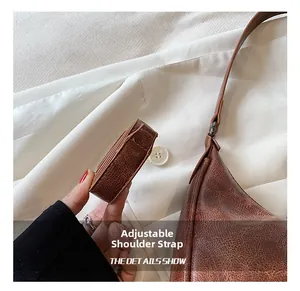 Détail de la bandoulière réglable sur le sac sous le bras en cuir marron vintage