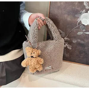 Detail of grey faux fur bucket bag with plush bear charm and woven label decoration