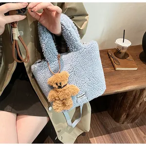 Detail of light blue fuzzy bucket bag with cute bear charm and woven cross-body strap