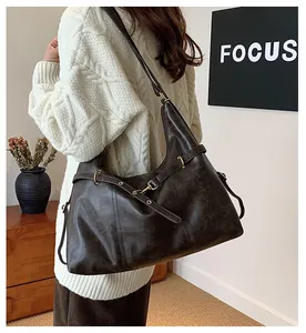 Detail view of large caramel brown retro leather tote bag with metal buckle straps