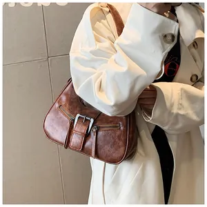 Détail d'un sac demi-lune vintage en cuir ciré marron avec boucle en métal et zips décoratifs
