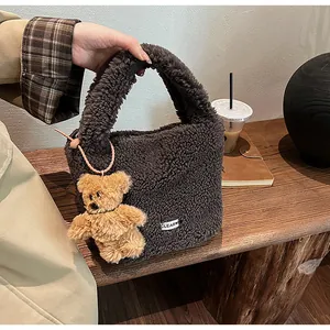 Detail of plush faux lamb wool bucket bag in dark brown with cute bear keychain and label