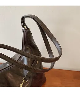 Detail of dark brown vintage faux leather shoulder bag with sturdy handle and gold hardware