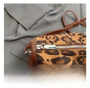 Détail du sac cylindre imprimé léopard avec fermeture éclair argentée et bord en cuir