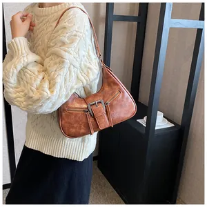Vue détaillée du sac sous le bras marron vintage avec boucle sur un pull en maille
