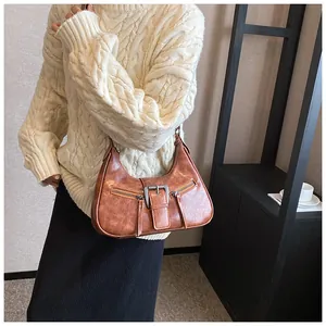 Détail du sac sous l'aisselle en cuir marron vintage avec boucles et fermetures éclair