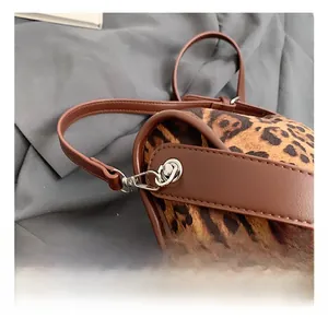 Détail du sac en daim léopard avec bordure en cuir marron et crochet métallique argenté