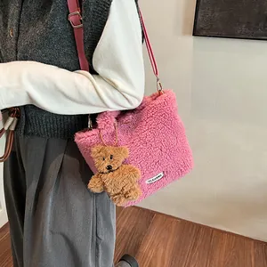 Pink plush lamb wool bucket bag with cute bear charm shown on a female model