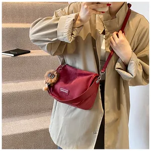 Détail du sac à bandoulière en daim rouge avec une breloque lion en peluche douce