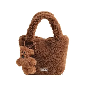 Brown teddy fleece bucket bag with cute bear charm and woven label on white background