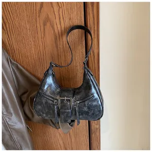 Détail du sac croissant vintage noir avec boucle argentée suspendu à une porte
