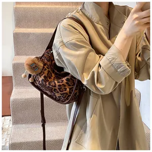 Gros plan d'un sac bandoulière léopard porté avec un trench-coat kaki élégant