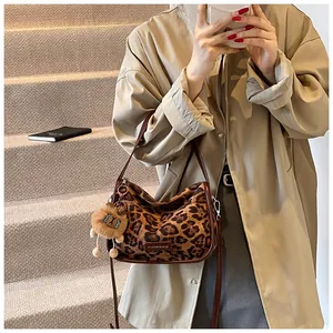 Détail du sac bandoulière en daim léopard avec breloque lion et bandoulière en cuir brun
