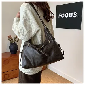 Side view of a vintage dark leather tote bag worn by a model in a minimalist room