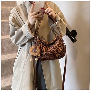 Détail du sac bandoulière en daim léopard avec pendentif ours et plaque de marque