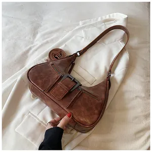 Détail du sac demi-lune vintage marron avec boucle en métal sur un blazer beige