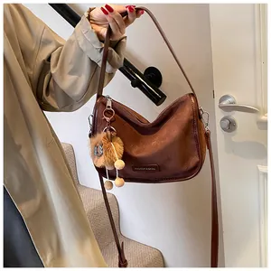 Détail du sac demi-lune en daim marron café avec charm lion et fermeture éclair