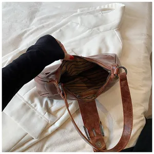 Détail d'un sac demi-lune vintage marron avec boucle en métal et doublure rayée