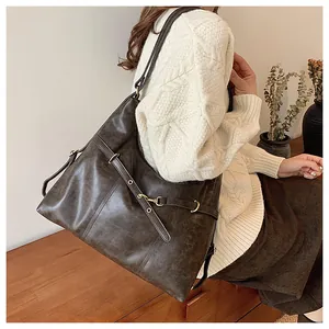 Close-up of a large dark brown leather tote bag with vintage texture and metal buckle